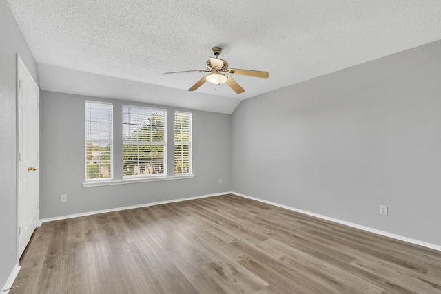 empty room featuring ceiling fan, a textured ceiling, lofted ceiling, and hardwood / wood-style floors