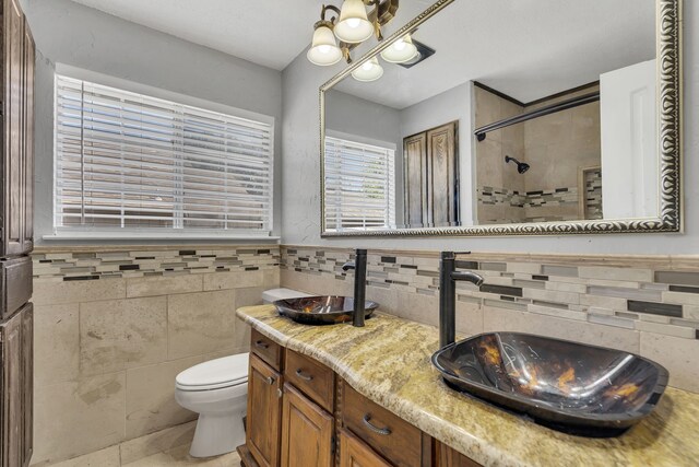 bathroom featuring tile walls, vanity, a tile shower, toilet, and tile patterned floors