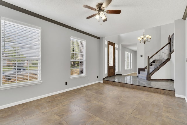 tiled entrance foyer featuring ceiling fan with notable chandelier, ornamental molding, a textured ceiling, and a healthy amount of sunlight