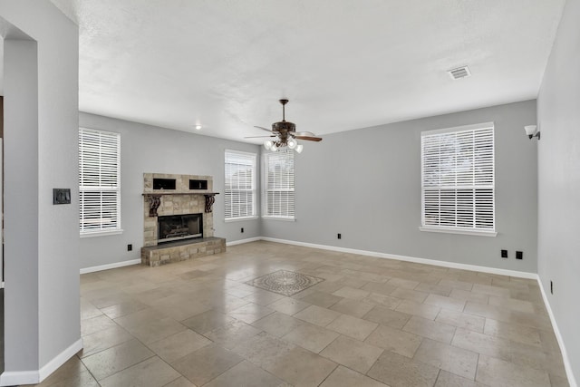 unfurnished living room featuring ceiling fan and a stone fireplace