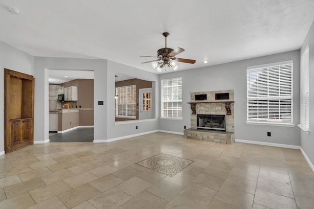 unfurnished living room with a stone fireplace and ceiling fan