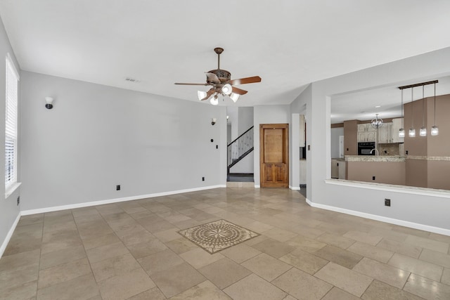 unfurnished living room with ceiling fan with notable chandelier