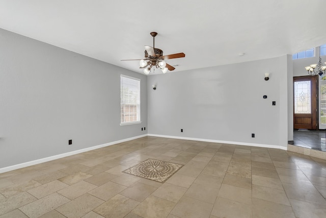 tiled spare room with ceiling fan with notable chandelier