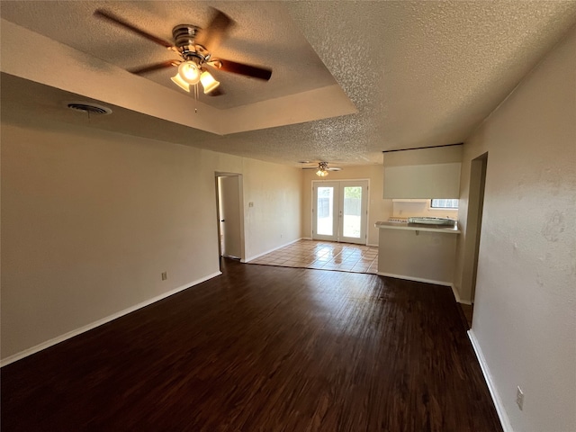 empty room with ceiling fan, a textured ceiling, dark hardwood / wood-style floors, and french doors