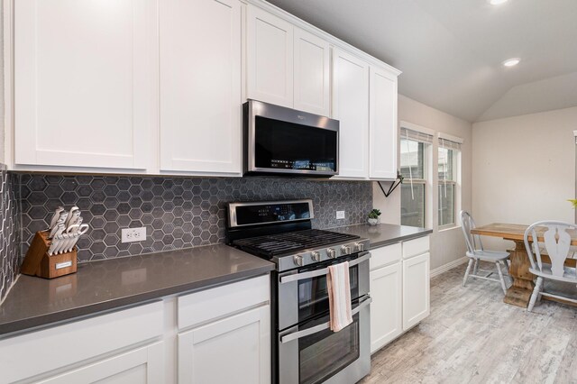 641 Fletcher Dr, Fate, TX 75087 - kitchen with dark countertops, backsplash, light wood-style floors, white cabinetry, and appliances with stainless steel finishes