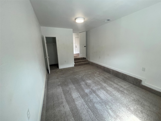 unfurnished bedroom featuring dark carpet and a closet