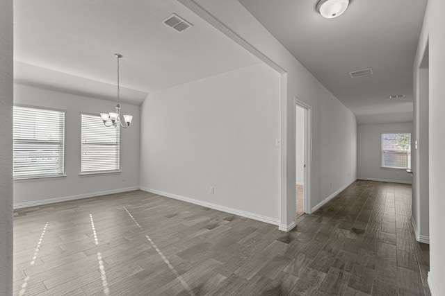 unfurnished room with wood-type flooring and a notable chandelier