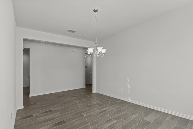 empty room with an inviting chandelier and dark wood-type flooring