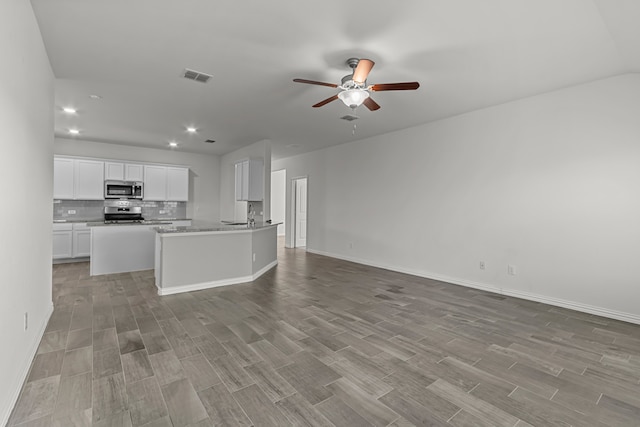 kitchen featuring light hardwood / wood-style floors, white cabinets, stainless steel appliances, backsplash, and ceiling fan