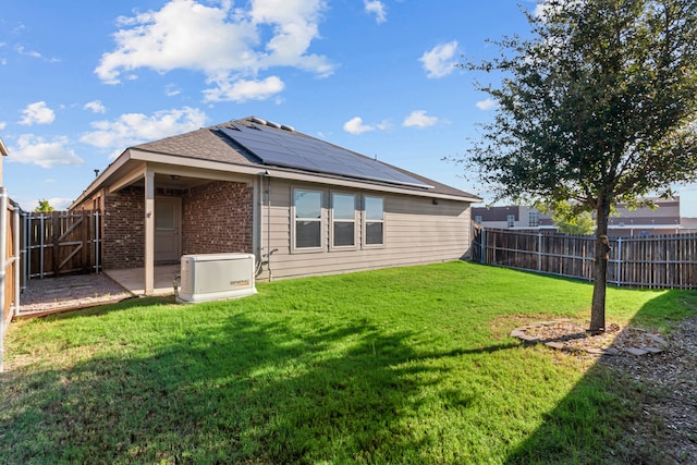 back of property featuring solar panels and a lawn