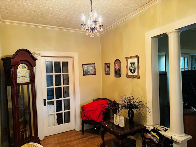 interior space with a notable chandelier, crown molding, ornate columns, and hardwood / wood-style flooring