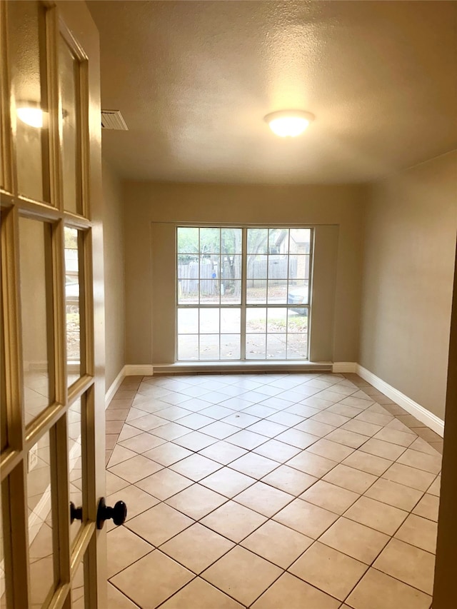 tiled empty room with a textured ceiling