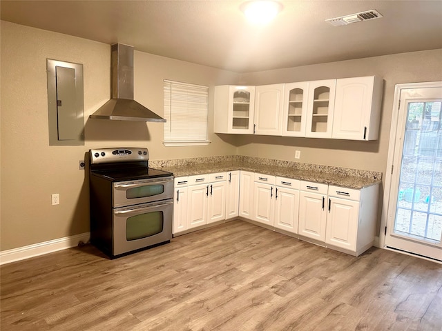 kitchen with a wealth of natural light, stainless steel electric range oven, electric panel, and wall chimney range hood