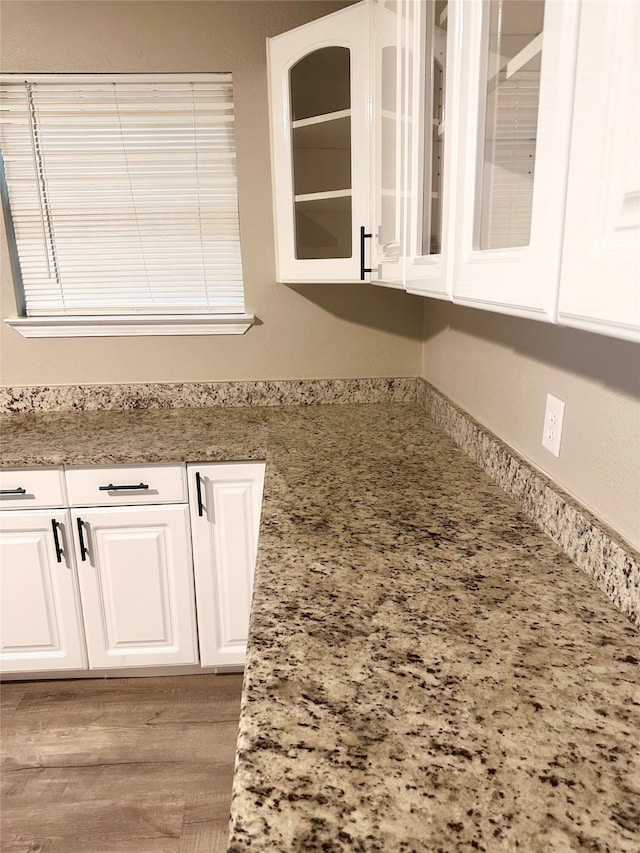 kitchen featuring light hardwood / wood-style flooring, light stone counters, and white cabinets