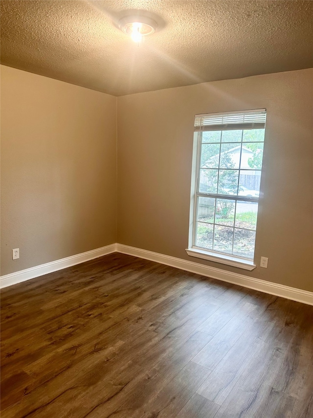 spare room featuring a textured ceiling and dark hardwood / wood-style floors