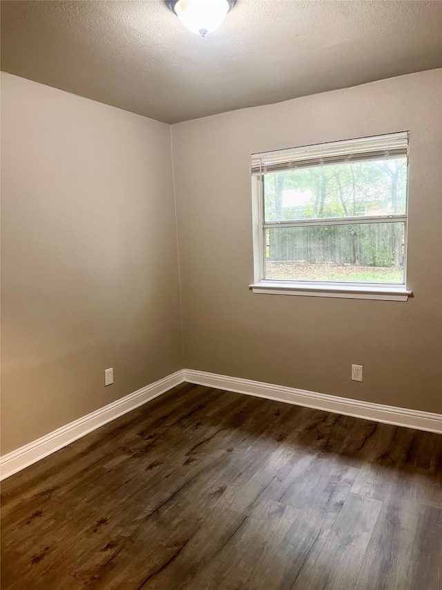 empty room with a textured ceiling and dark hardwood / wood-style flooring