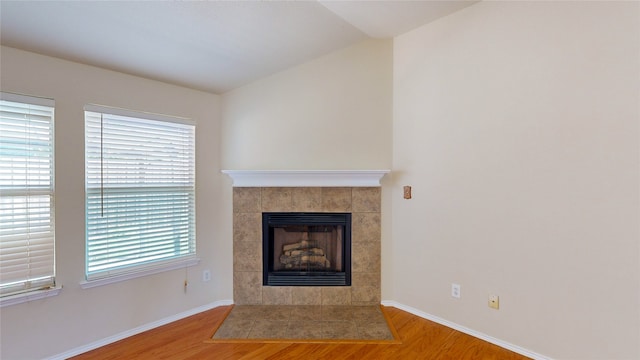 unfurnished living room featuring wood-type flooring, a fireplace, and vaulted ceiling