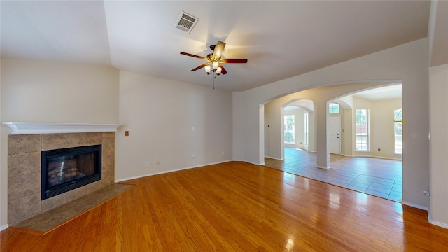 unfurnished living room with a tiled fireplace, ceiling fan, and hardwood / wood-style flooring