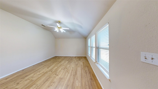 empty room with ceiling fan, light wood-type flooring, and vaulted ceiling