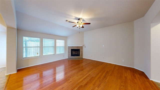 unfurnished living room with ceiling fan, lofted ceiling, a tiled fireplace, and light hardwood / wood-style floors