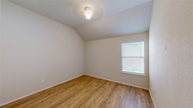 spare room with vaulted ceiling and light hardwood / wood-style floors