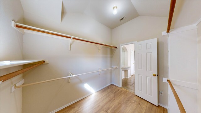 spacious closet featuring light hardwood / wood-style flooring and lofted ceiling