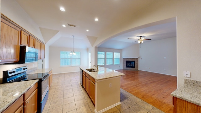 kitchen featuring hanging light fixtures, a tiled fireplace, stainless steel appliances, ceiling fan, and light hardwood / wood-style flooring