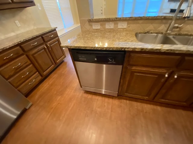 kitchen with dishwasher, light hardwood / wood-style floors, sink, and decorative backsplash