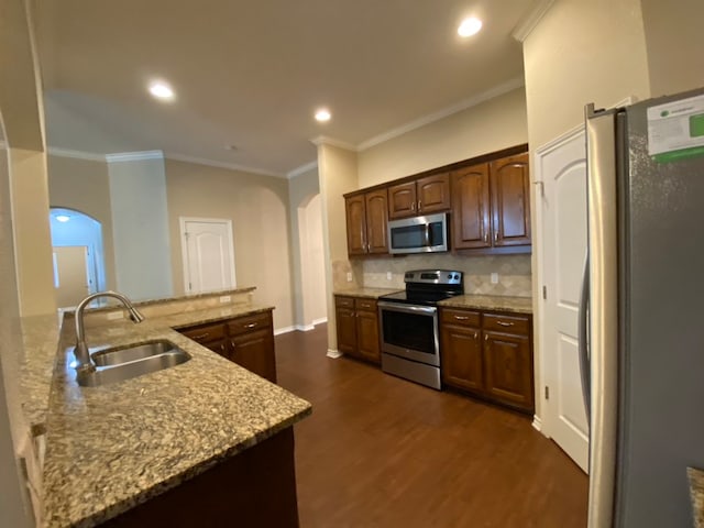 kitchen featuring light stone counters, sink, dark wood-type flooring, stainless steel appliances, and crown molding