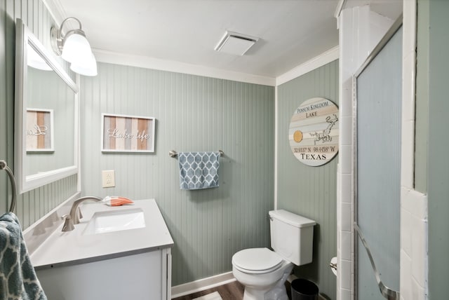 bathroom with crown molding, vanity, toilet, and a shower with shower door