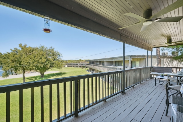 wooden terrace with ceiling fan and a yard