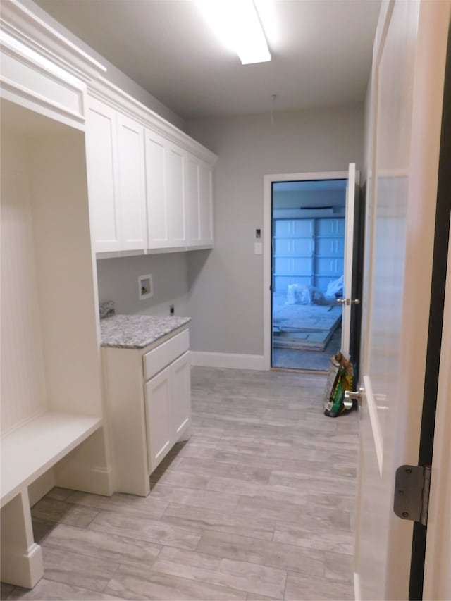 washroom featuring light wood-type flooring, washer hookup, and cabinets