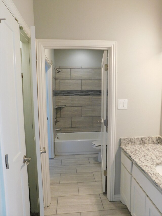 full bathroom featuring tiled shower / bath, vanity, and toilet