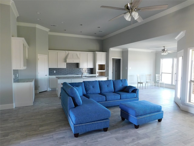 living room with ceiling fan, light hardwood / wood-style flooring, crown molding, and sink