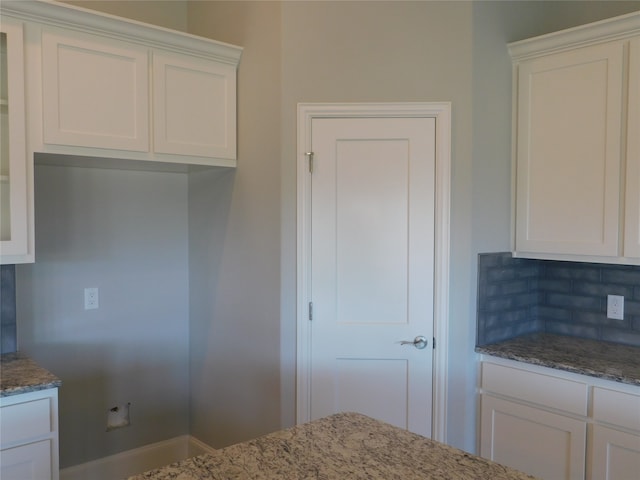 kitchen featuring light stone counters, white cabinets, and tasteful backsplash