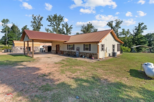 back of property with a lawn, a carport, and central air condition unit