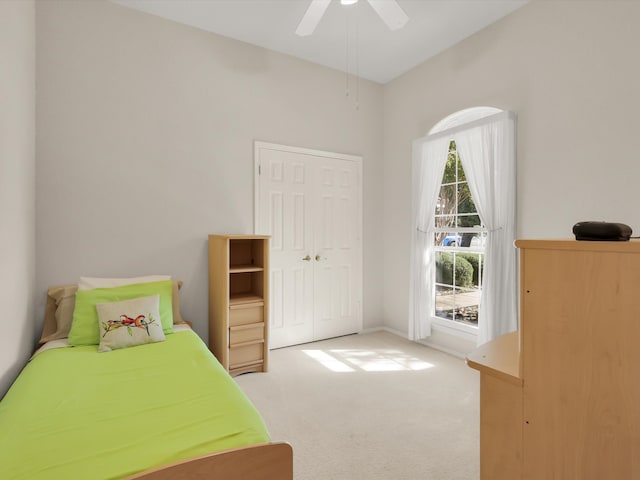 bedroom with ceiling fan, light colored carpet, and a closet