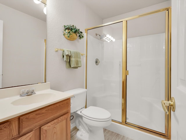 bathroom with wood-type flooring, walk in shower, vanity, and toilet