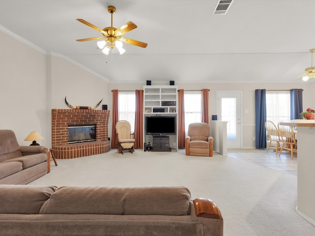 carpeted living room featuring a brick fireplace, ceiling fan, plenty of natural light, and crown molding