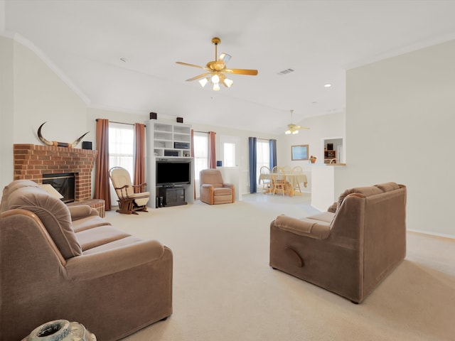 carpeted living room with a brick fireplace, ceiling fan, and crown molding