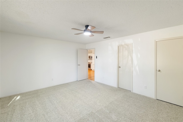 carpeted spare room with ceiling fan and a textured ceiling