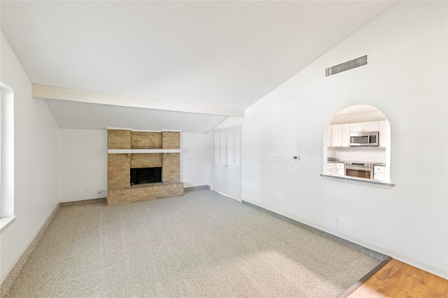 unfurnished living room with carpet flooring, lofted ceiling, and a fireplace