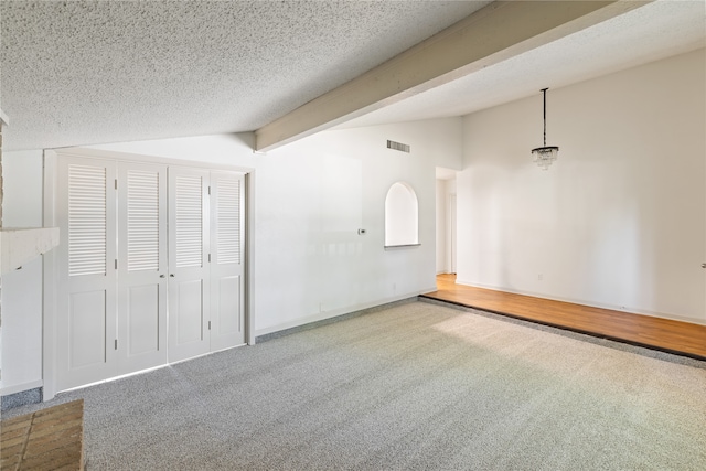 interior space with carpet floors, a textured ceiling, a closet, and lofted ceiling with beams