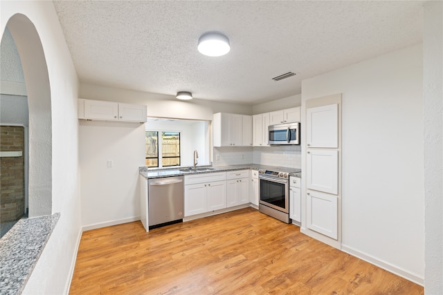 kitchen featuring a textured ceiling, sink, white cabinetry, light hardwood / wood-style flooring, and stainless steel appliances