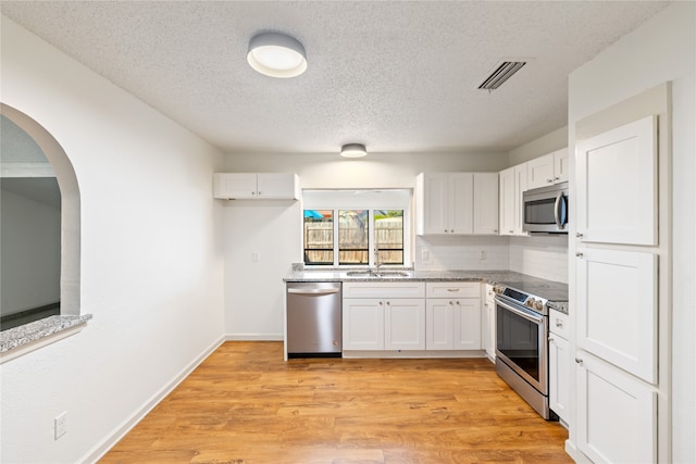 kitchen featuring light hardwood / wood-style flooring, a textured ceiling, appliances with stainless steel finishes, and white cabinetry