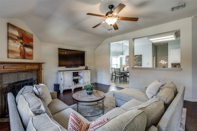 living room with dark wood-type flooring, vaulted ceiling, a fireplace, and ceiling fan with notable chandelier