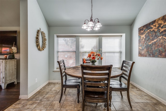 dining area with hardwood / wood-style flooring, a notable chandelier, and vaulted ceiling