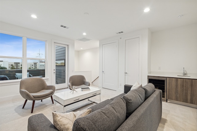 living room with light carpet, wine cooler, and bar