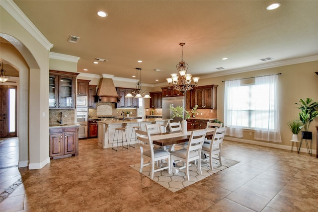 tiled dining area featuring crown molding, an inviting chandelier, and sink