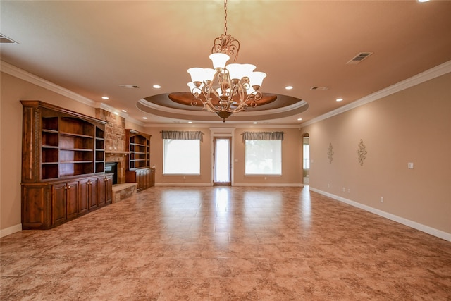 unfurnished living room featuring a chandelier, a tray ceiling, crown molding, and a stone fireplace